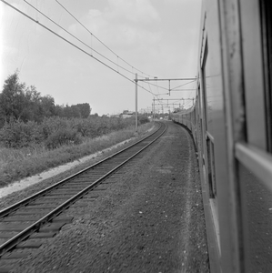 803853 Gezicht op de spoorlijn ten zuiden van Geldermalsen, vanuit een rijdende trein.